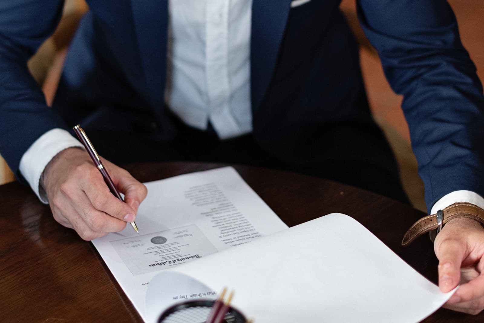 A hand signing an agreement at a desk